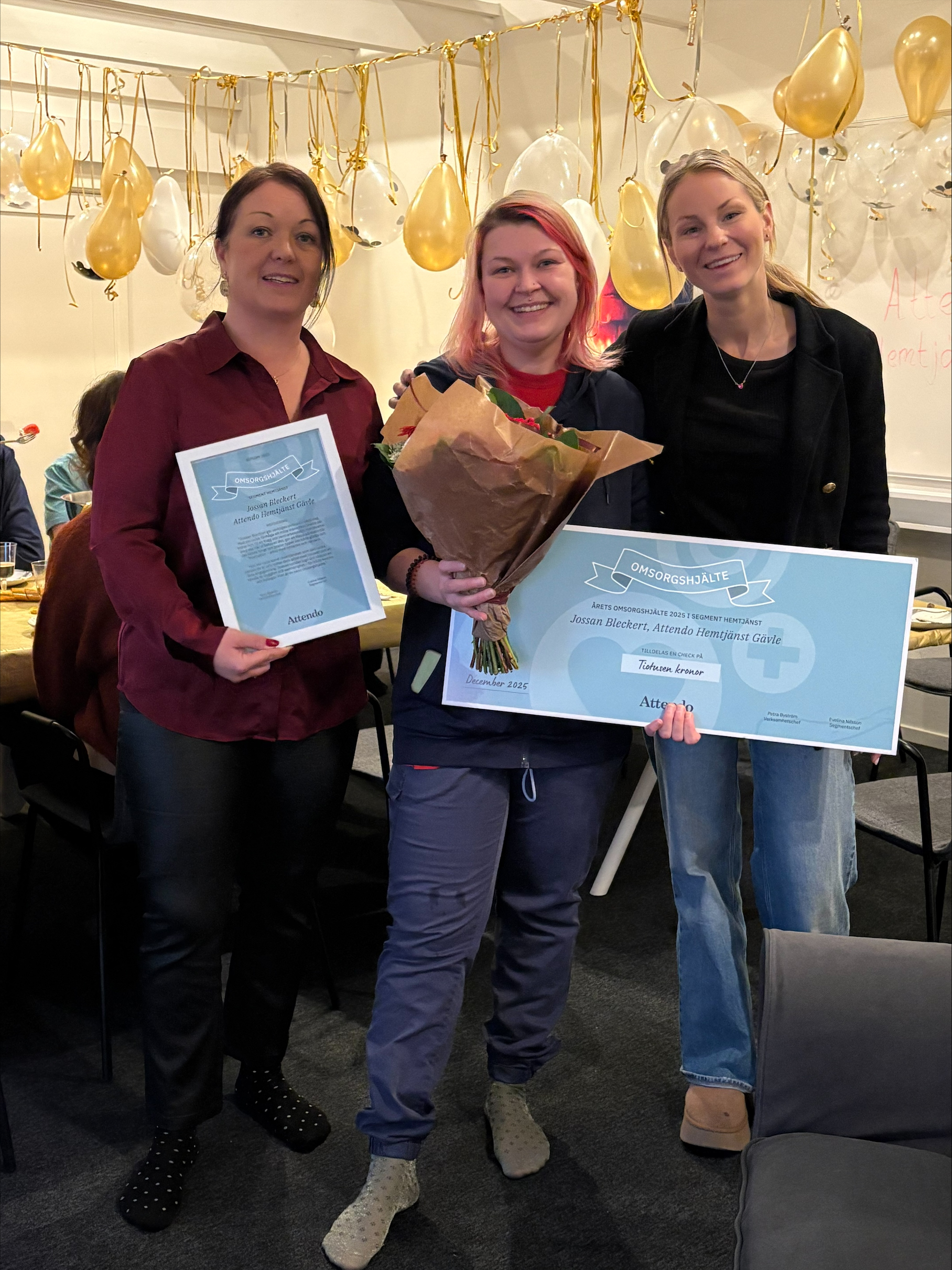 En leende Jossan Beckert med en stor check i handen, omringad av chefer som hyllar henne