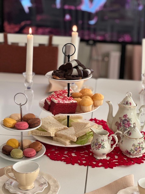 Ett dukat bord med kakfat i v&aring;ningar med godsaker p&aring;, och en te-servis med blomm&ouml;nster och t&auml;nda ljus