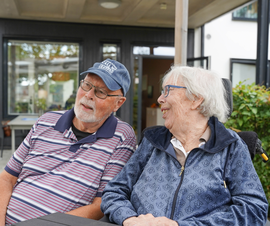 Äldre par sitter bredvid varandra och samtalar och skrattar