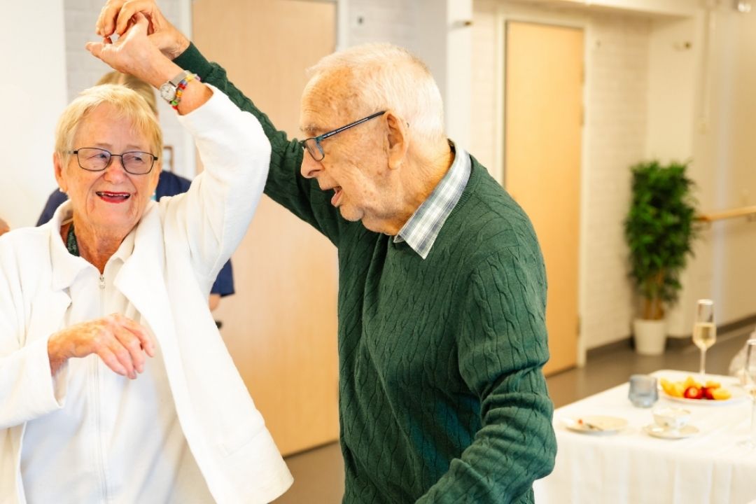 Pensionärer dansar tillsammans på ett äldreboende